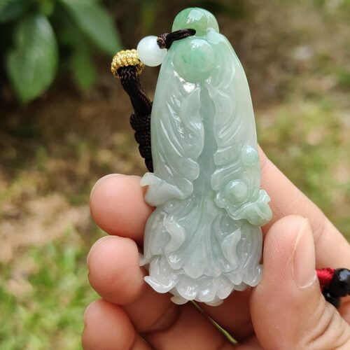 a hand holding a jade pendant