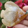 a hand holding a stone fish pendant