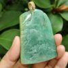 a hand holding a jade pendant