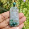 a hand holding a jade pendant