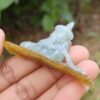 a hand holding a small jade sculpture