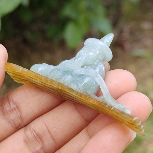 a hand holding a small jade sculpture