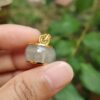 a hand holding a small round gold and silver pendant
