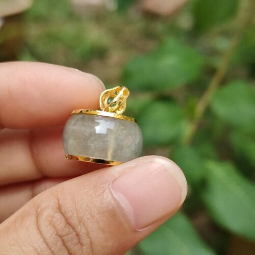 a hand holding a small round gold and silver pendant