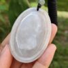 a hand holding a jade pendant