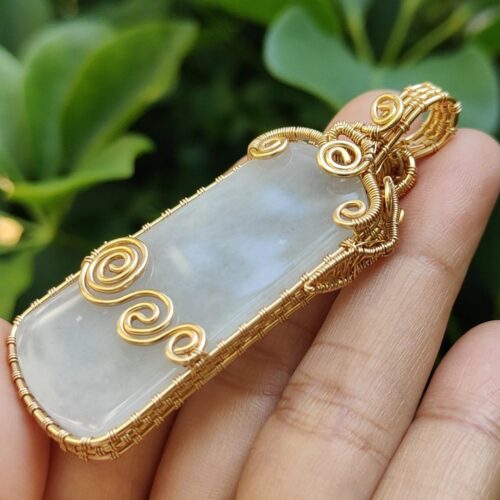 एक हाथ में सोने और सफेद रंग का पेंडेंट है