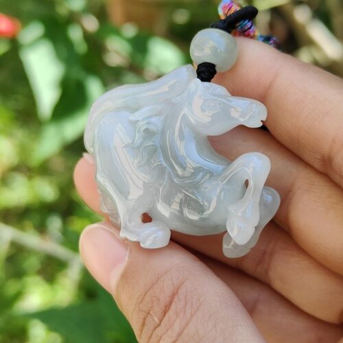 a hand holding a white horse pendant