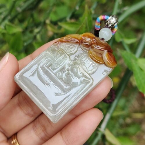 एक हाथ में जेड पेंडेंट थामे हुए