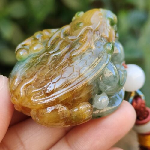 a hand holding a small frog shaped stone