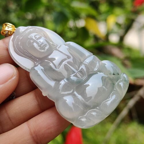 a hand holding a jade pendant
