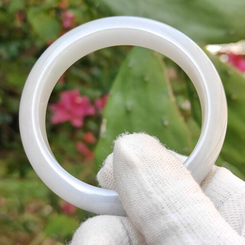 a hand wearing glove holding a white ring