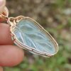 a hand holding a gold and blue pendant