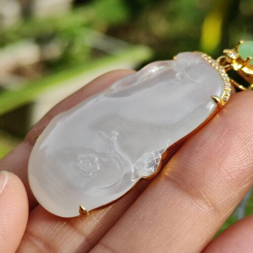 a hand holding a jade pendant