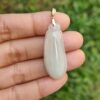 a hand holding a white pendant