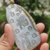 a hand holding a jade pendant