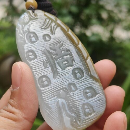a hand holding a jade pendant