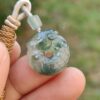 a hand holding a jade pendant