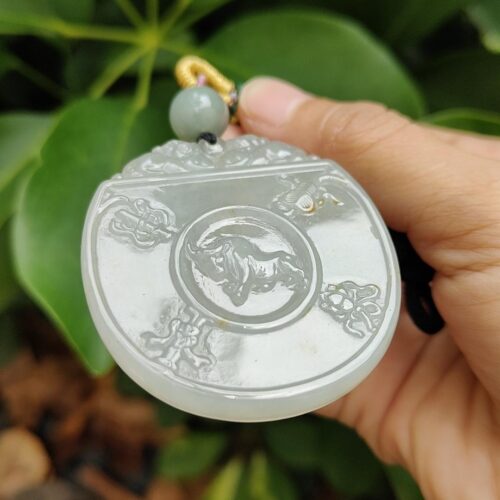 une main tenant un pendentif en jade