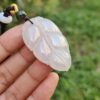 a hand holding a jade leaf pendant
