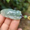 a hand holding a jade pendant