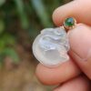 a hand holding a jade pendant