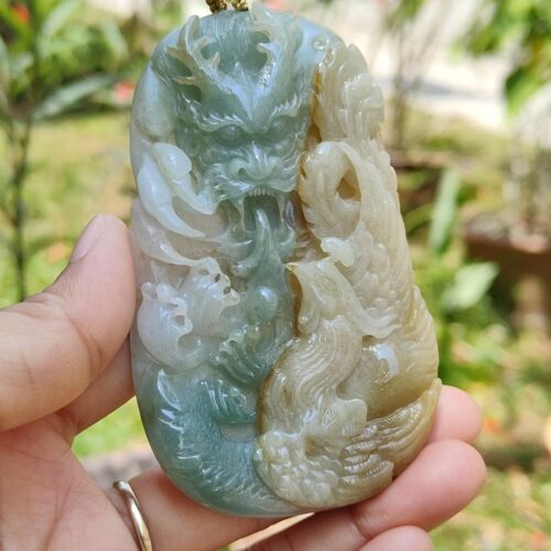 a hand holding a jade pendant