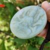 Una mano sosteniendo un medallón de jade.