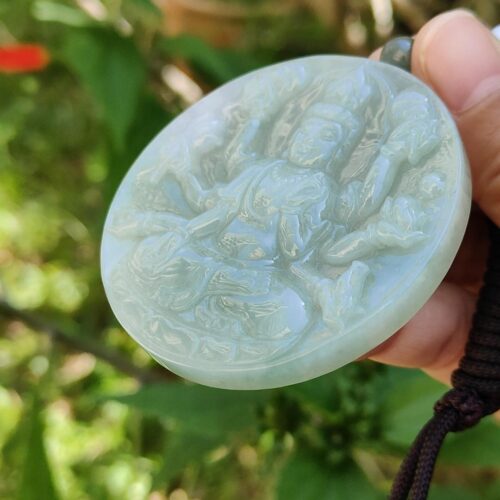 Una mano sosteniendo un medallón de jade.