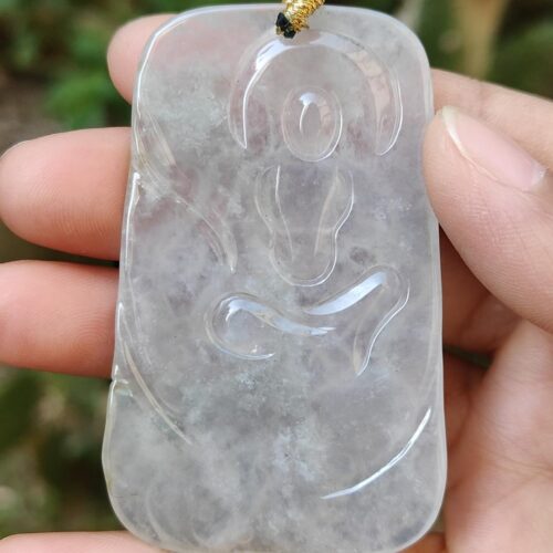 a hand holding a jade pendant