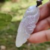 Una mano sosteniendo un colgante de piedra blanca.