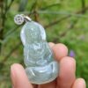 a hand holding a jade buddha pendant