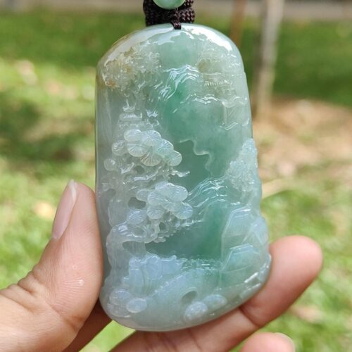 a hand holding a jade pendant