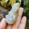 a hand holding a jade pendant