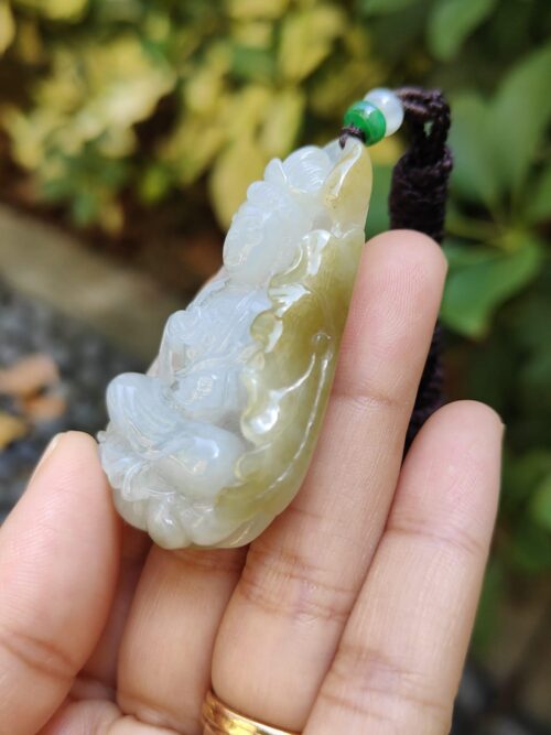 a hand holding a jade pendant