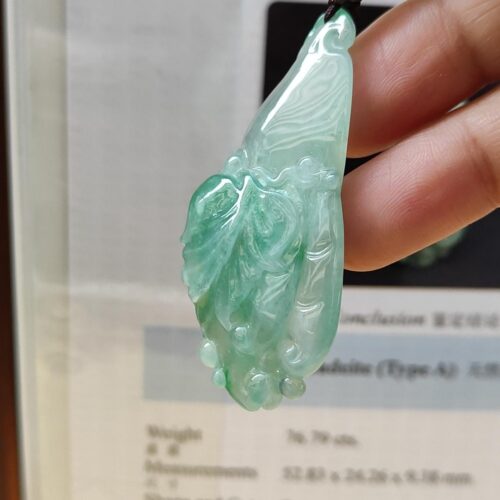 eine Hand, die einen Jadeanhänger hält