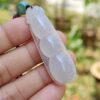 a hand holding a white jade necklace
