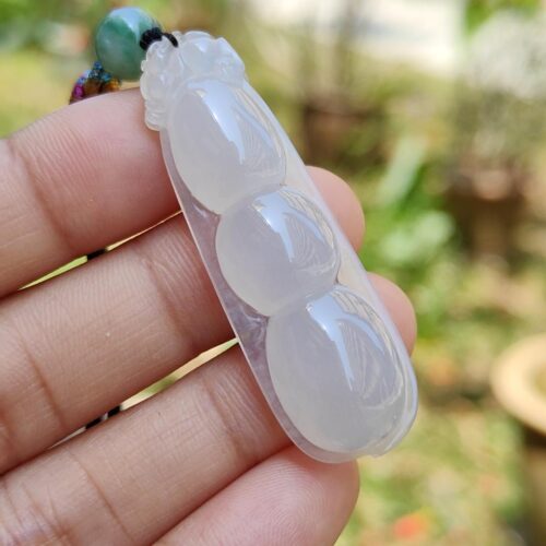 a hand holding a white jade necklace