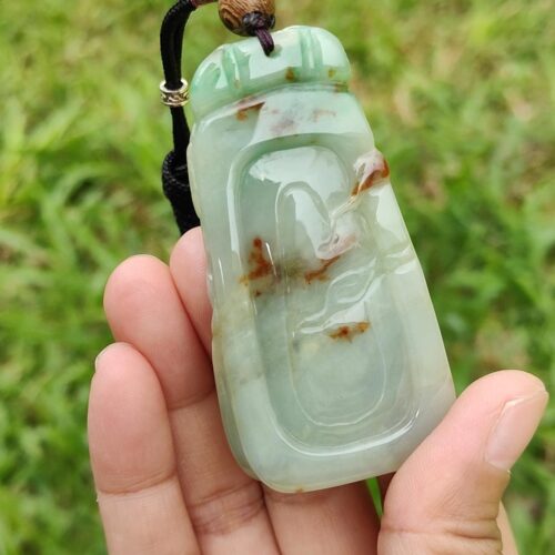 a hand holding a jade pendant