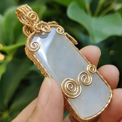 एक हाथ में पेंडेंट पकड़े हुए