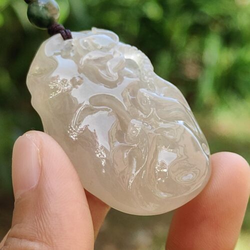 a hand holding a jade pendant