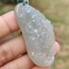 a hand holding a jade pendant
