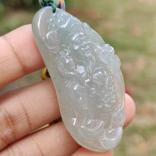 a hand holding a jade pendant