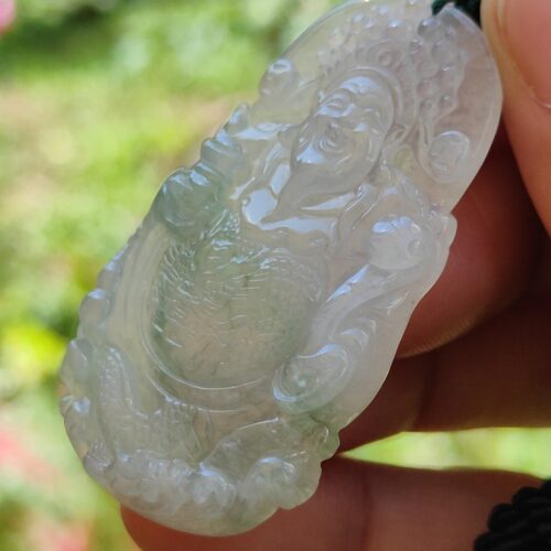 a hand holding a jade pendant