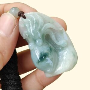 a hand holding a jade pendant