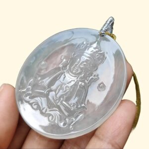a hand holding a round pendant