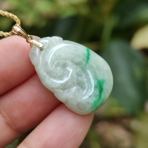 a hand holding a jade pendant