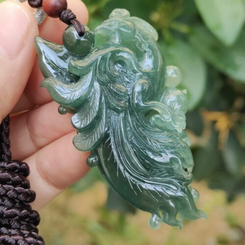 a hand holding a jade pendant