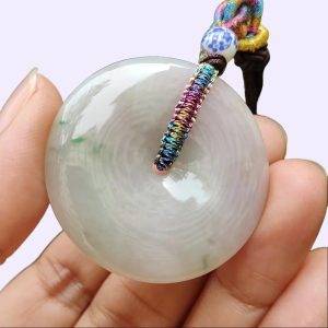 a hand holding a white round object with a colorful rope around it