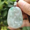 a hand holding a jade pendant