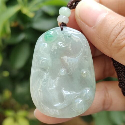 a hand holding a jade pendant